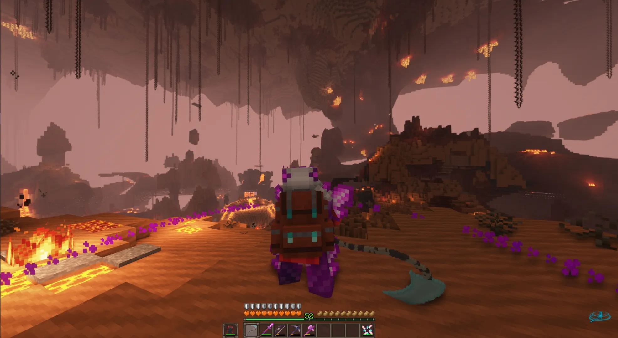 A player in red and purple gear walks a lava-lit ridge in a vast cavern hung with chains and glowing ore